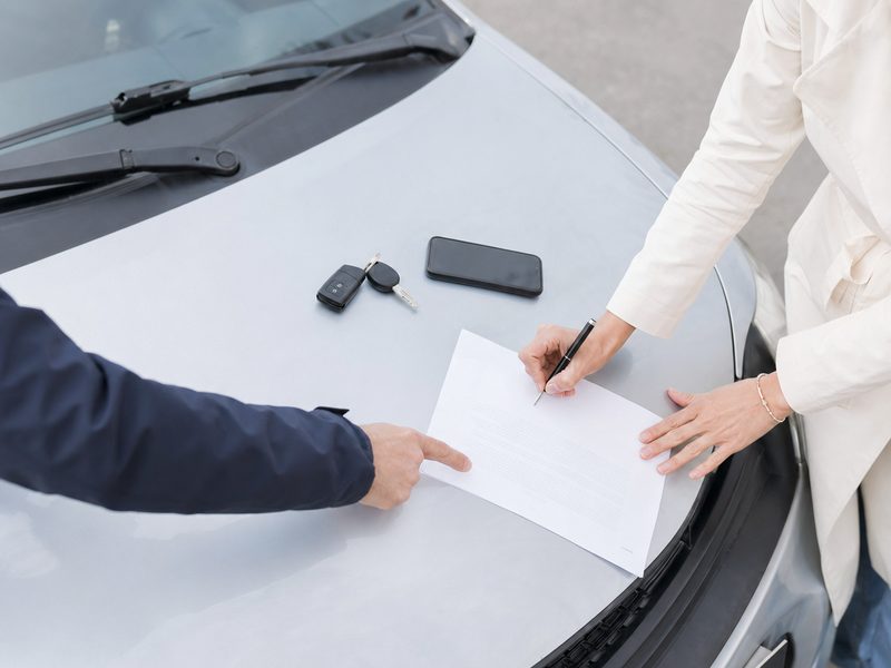 Signing a bill of sale on the hood of a car